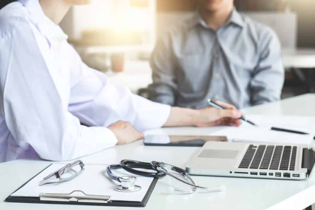 Healthcare and Medical concept, patient listening intently to a female doctor explaining patient symptoms or asking a question as they discuss paperwork together in a consultation