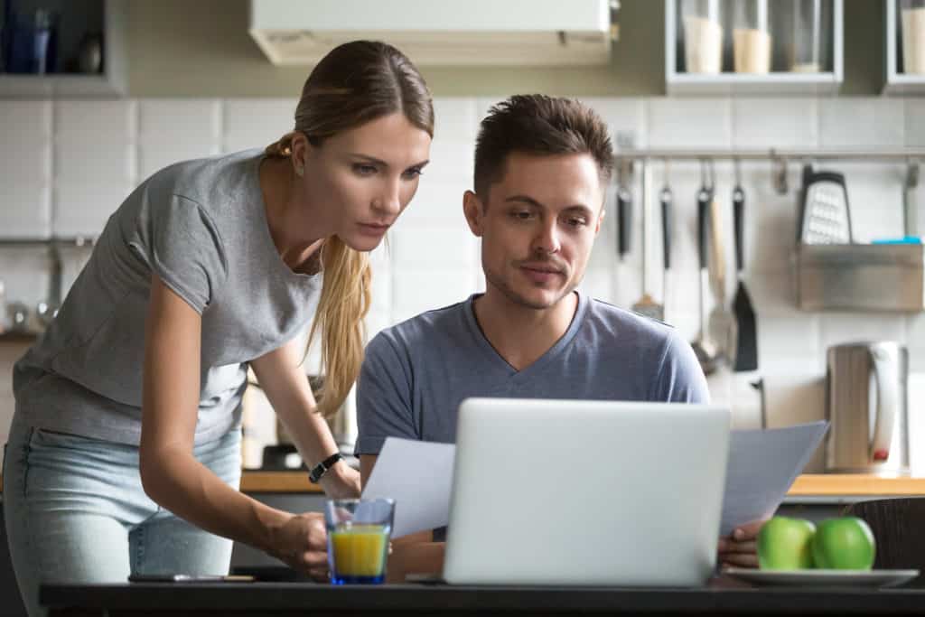 Serious couple holding documents using online application for pa